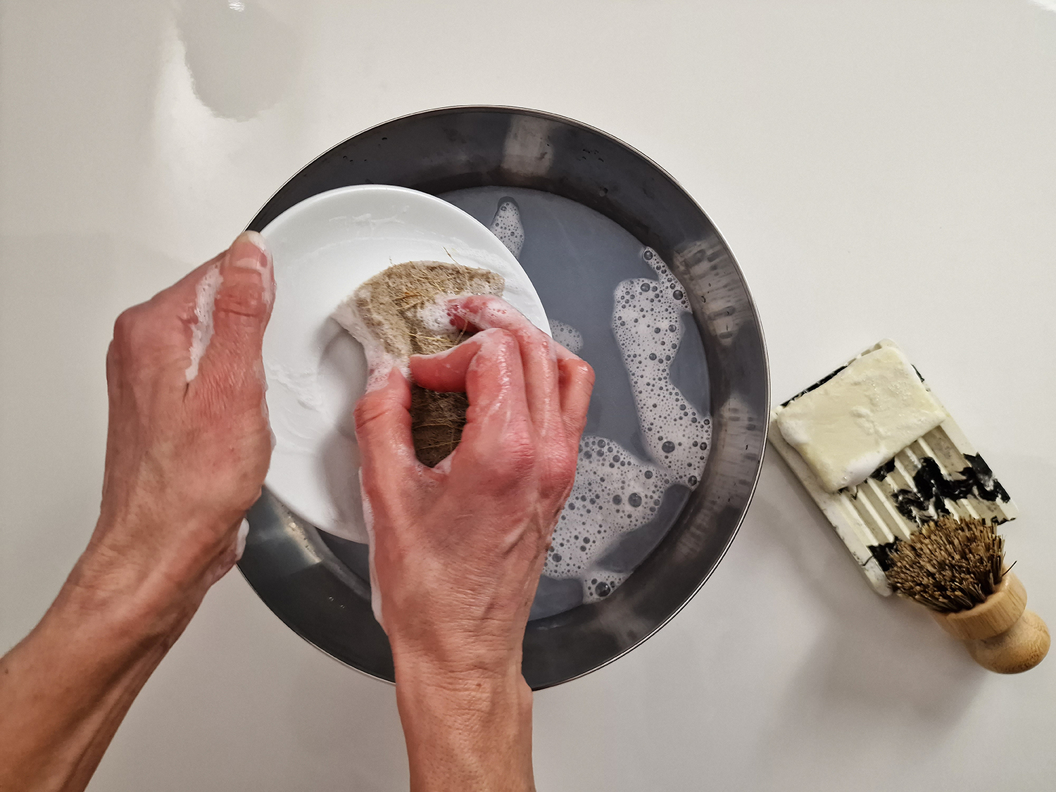 Vierka umýva riad s použitím tuhého mydla na riad, ktoré si sama vyrobila so surovinami z Handymade.